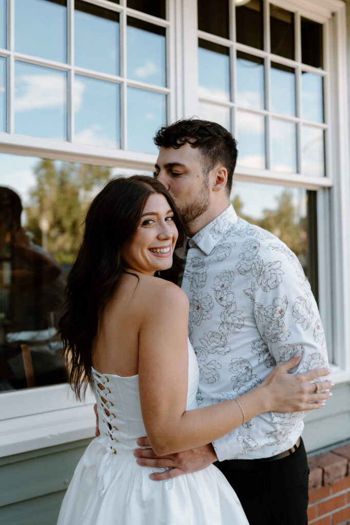 Fiancé kissing fiancée's forehead while she smiles during engagement session on Pearl Street