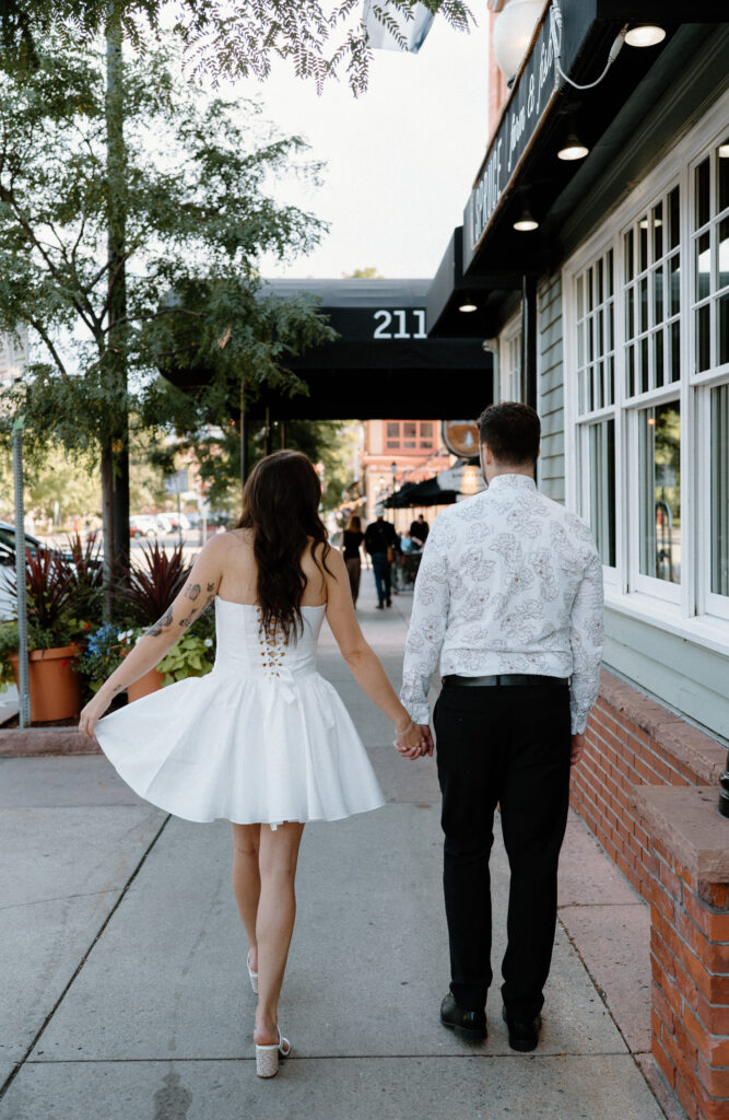 Couple holding hands and walking on Pearl Street during engagement session 