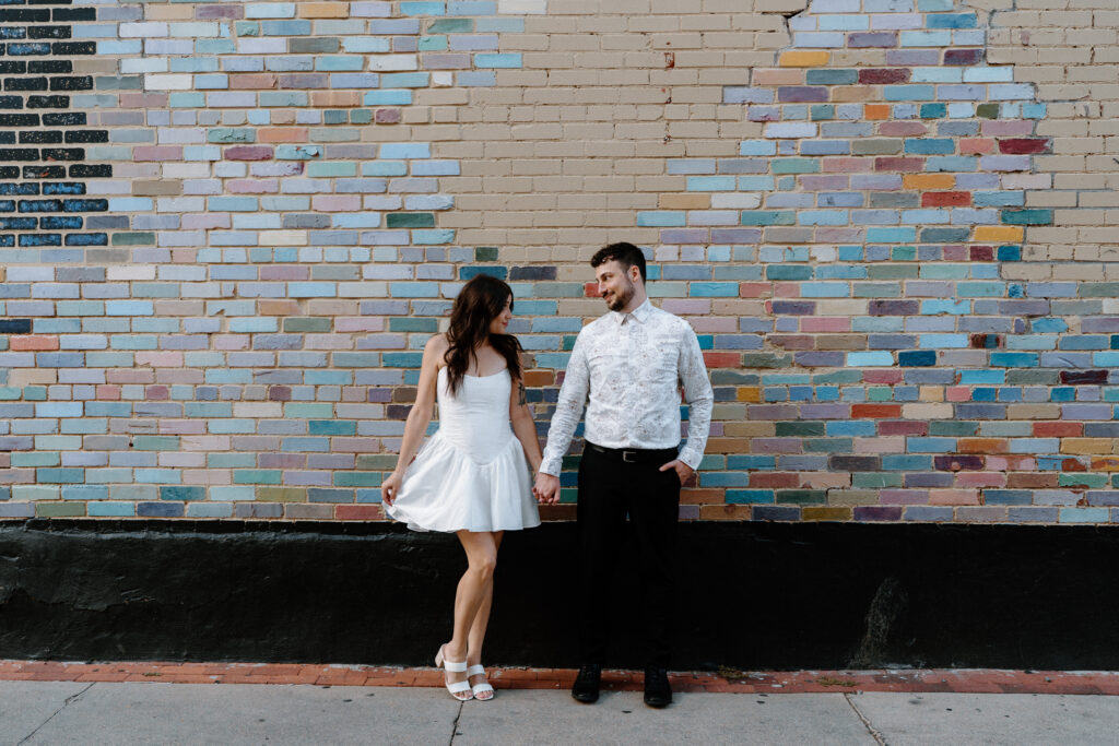 Couple holding hands and looking at each other on Pearl Street during engagement session