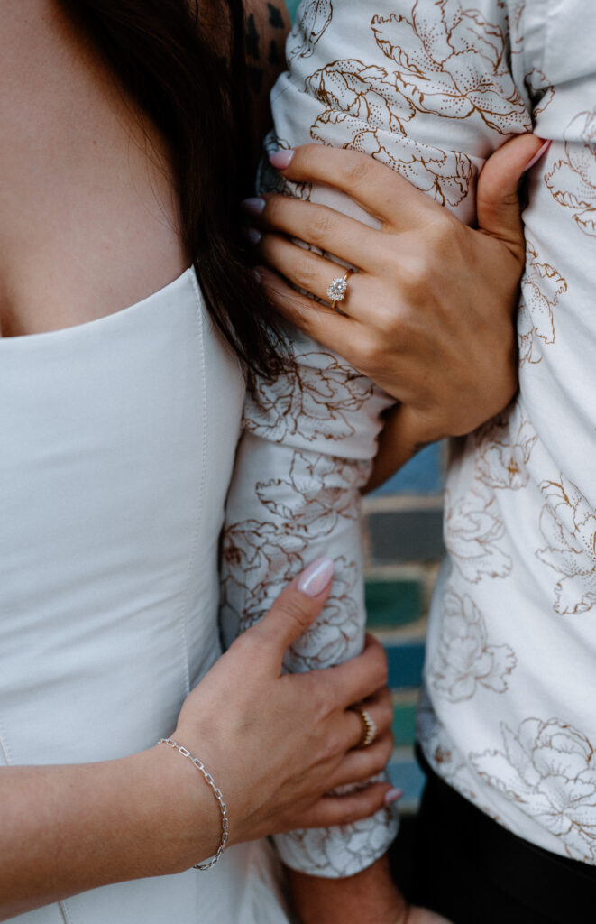 Couple's arms showing engagement ring during engagement session on Pearl Street
