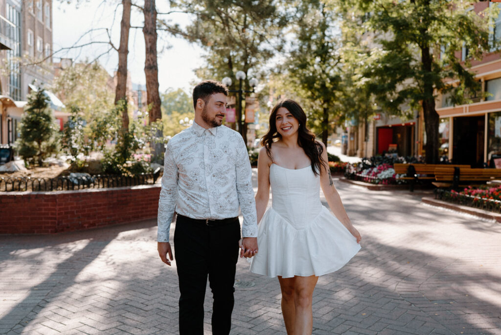 Couple smiling and holding hands during an engagement session on Pearl Street