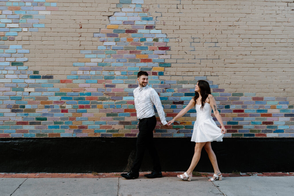 Couple holding hands and smiling during engagement session on Pearl Street