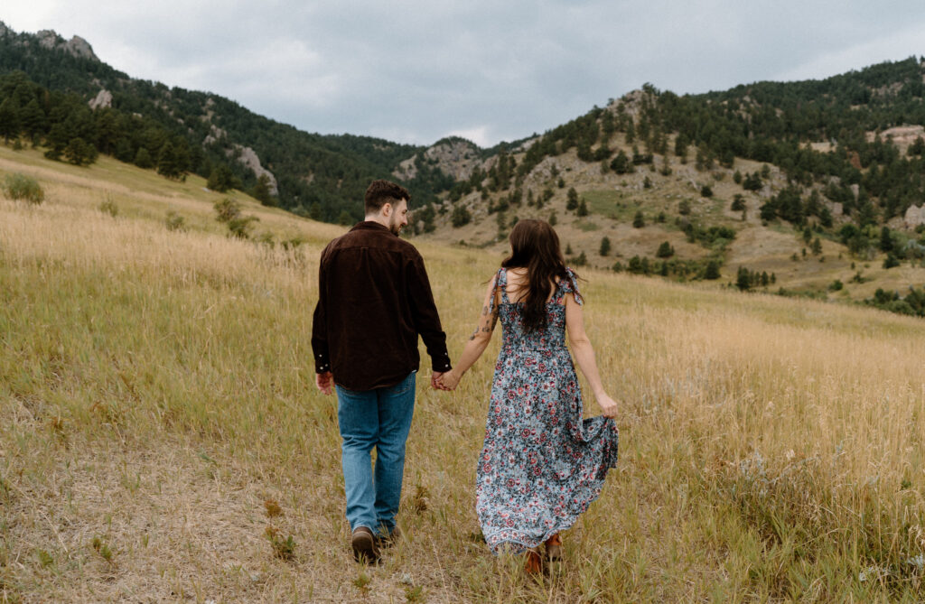 Couple hiking in a field during engagement session in Boulder, CO