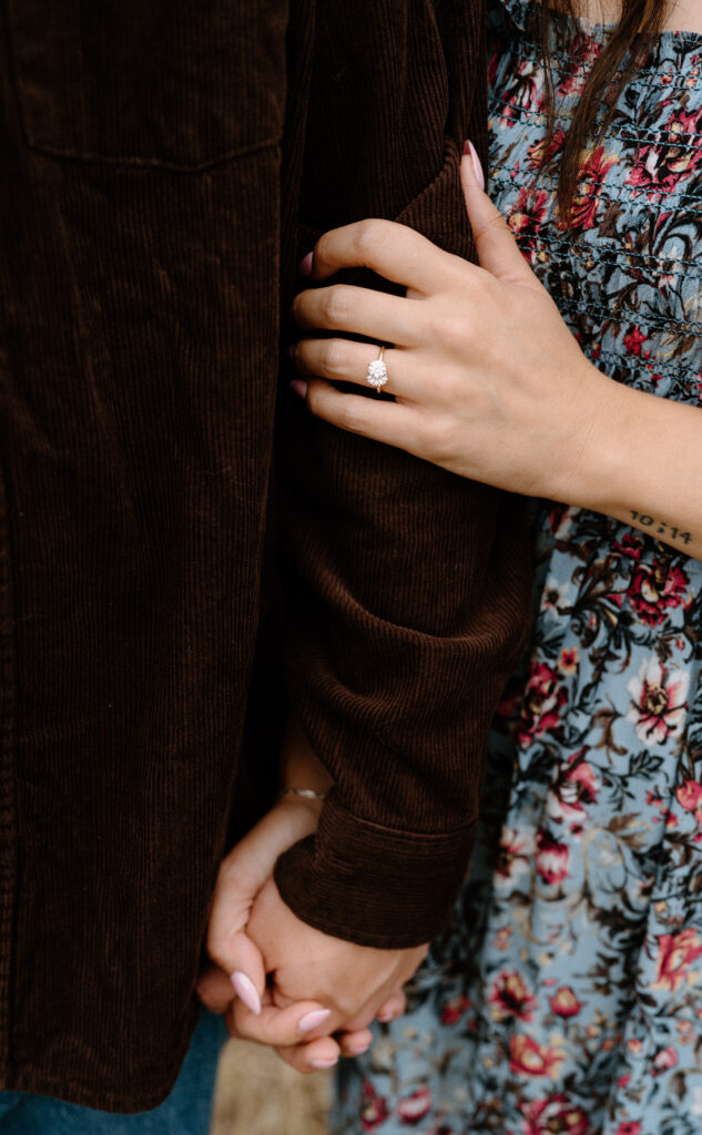 Fiancée holding fiancé's arm showing engagement ring during a session in Boulder, CO