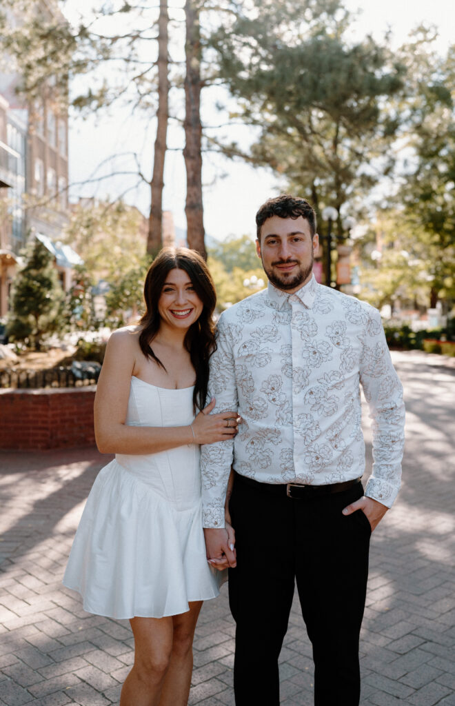Couple smiling at the camera during engagement session on Pearl Street