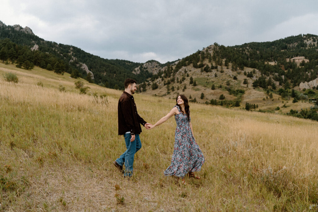 Couple walking in a field smiling during engagement session in Boulder, CO