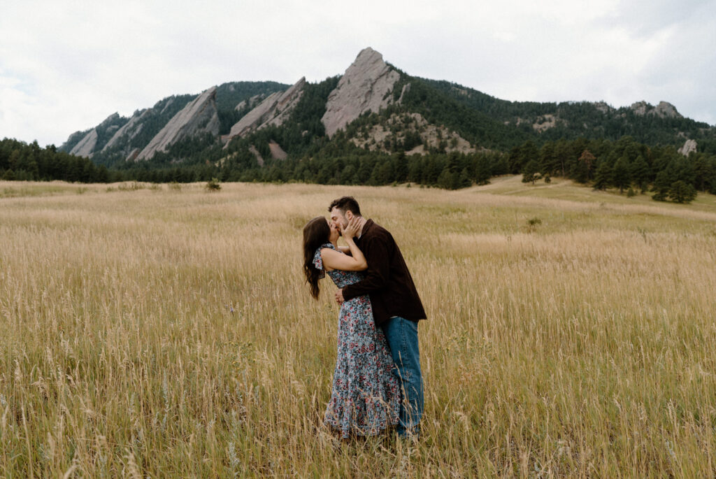 Couple kissing in front of Flat Irons during engagement session in Boulder, CO