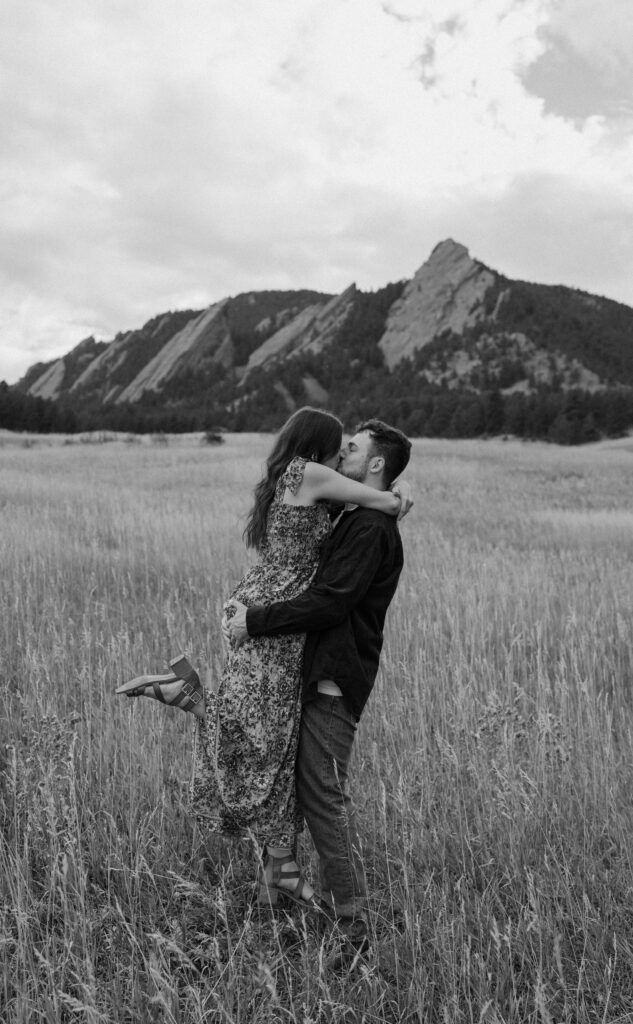 Fiancé picking fiancée up in a field during an engagement session in Boulder, CO