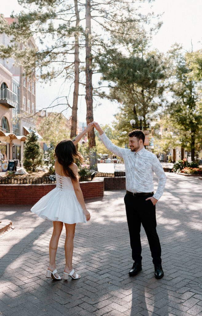 Fiancé twirling fiancée on Pearl Street during engagement session