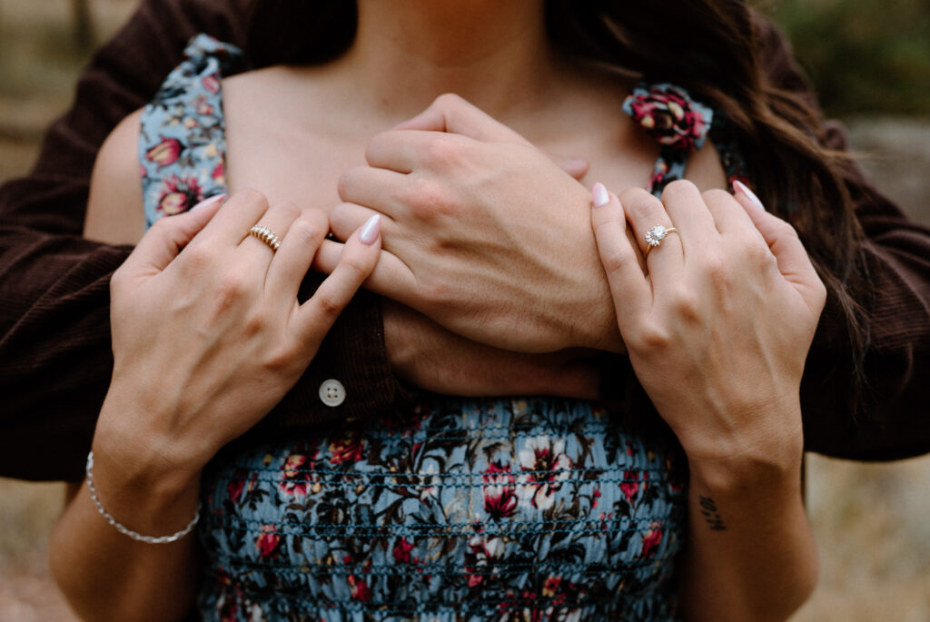 Couple hugging over the shoulder showing engagement ring during session in Boulder, CO