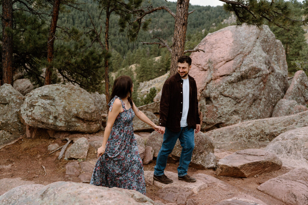 Couple hiking up rocks in Boulder, CO during engagement session