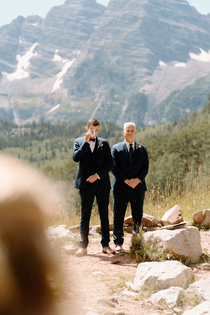 Groom crying while watching bride walk down the aisle during an elopement at Maroon Bells
