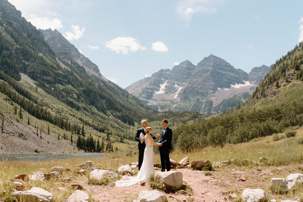 Bride and groom holding hands during ceremony during elopement at Maroon Bells