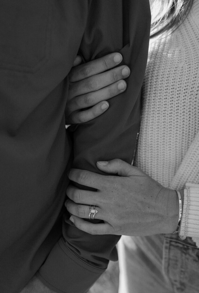 Fiancée holding fiancé's arm showing ring during engagement session at Poudre Canyon