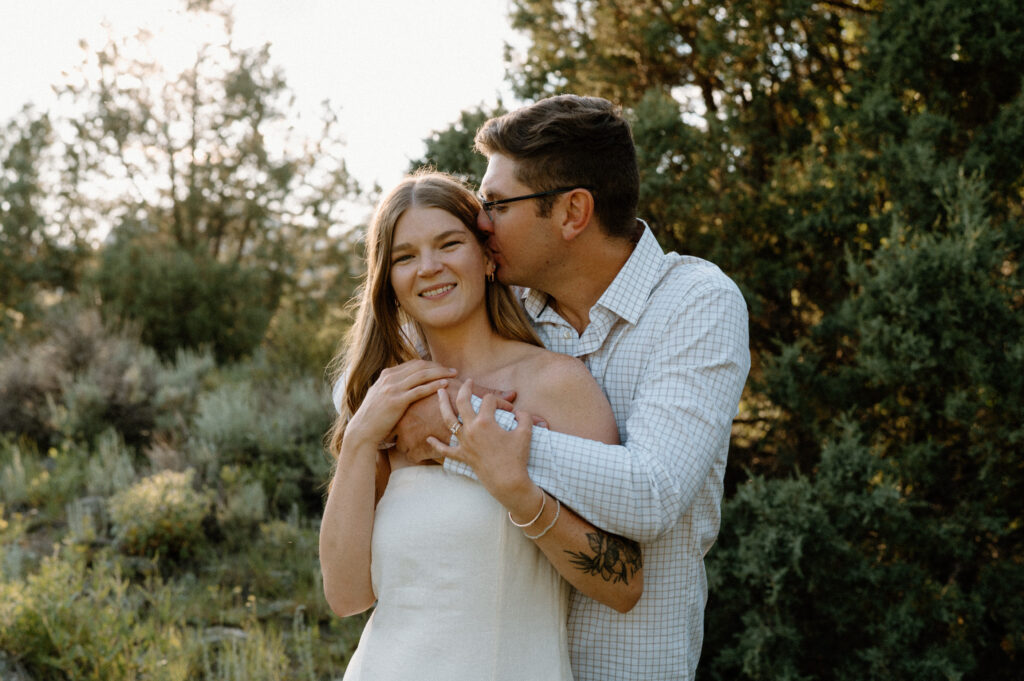 Fiancé hugging and kissing fiancées forehead during engagement session at Poudre Canyon