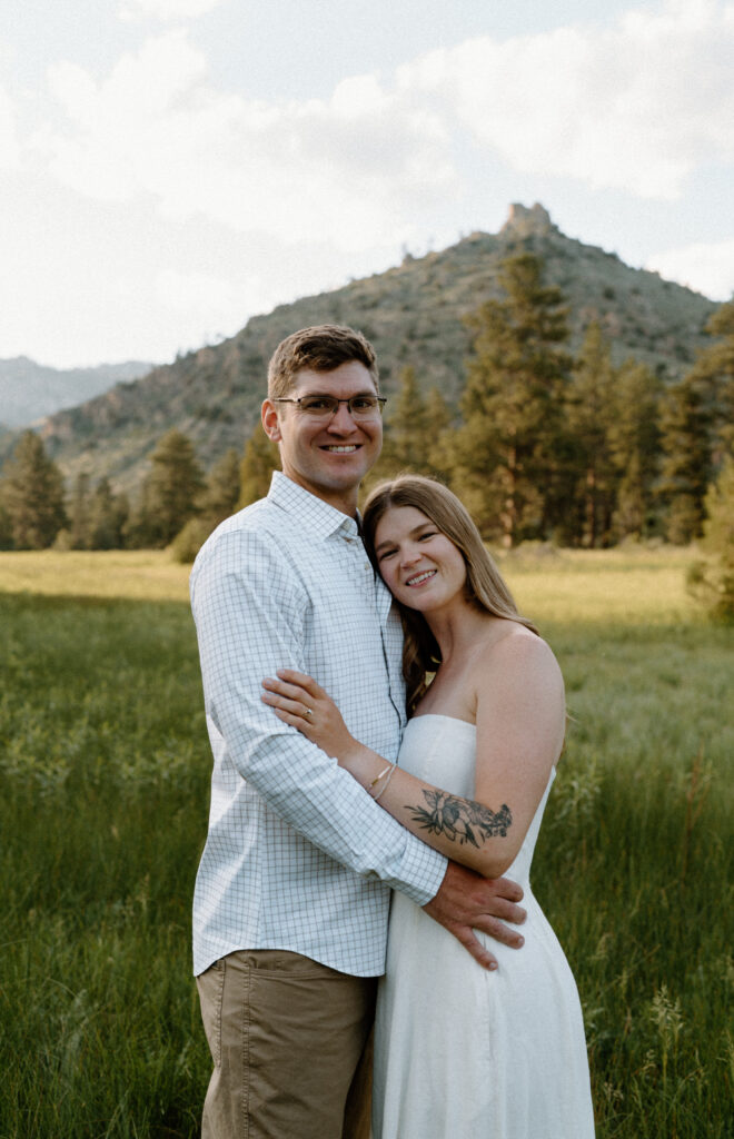 Couple hugging and smiling at camera during engagement session at Poudre Canyon