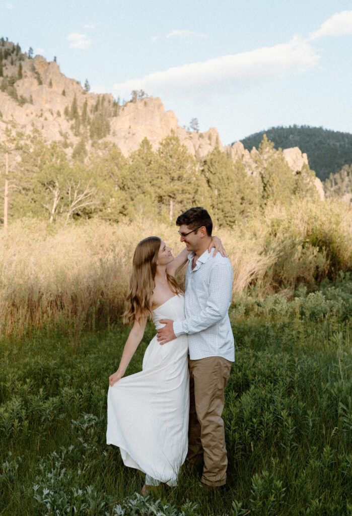 Couple smiling at each other and hugging during engagement session at Poudre Canyon