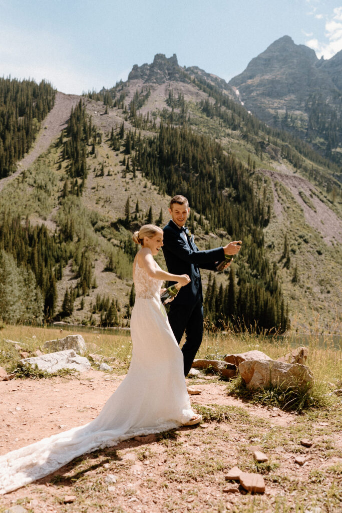 Bride and groom trying to pop champagne bottle during an elopement at Maroon Bells