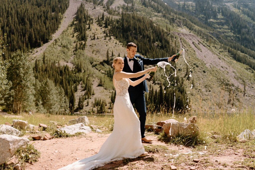 Bride and groom popping champagne bottles after elopement ceremony at Maroon Bells