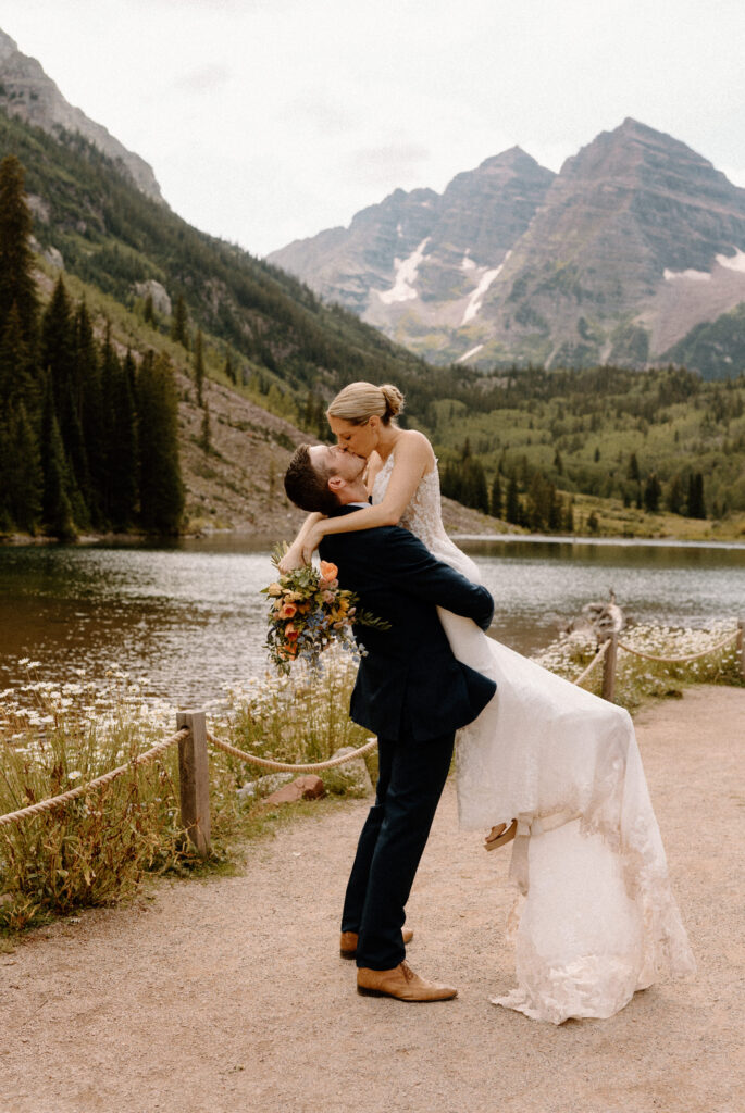 Groom picking up bride and kissing her during elopement at Maroon Bells