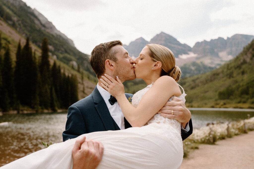 Groom kissing bride and holding bride during elopement at Maroon Bells