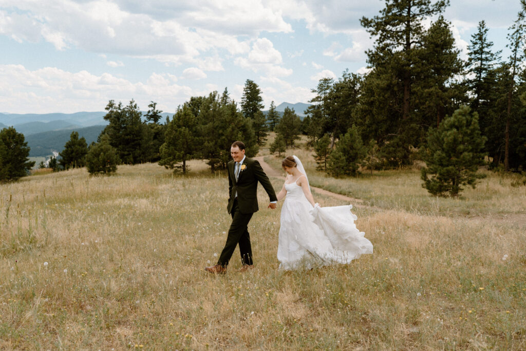 Bride and groom walking in a field at Mt. Falcon on wedding day