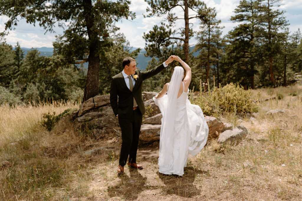 Groom twirling bride at Mt. Falcon on wedding day 