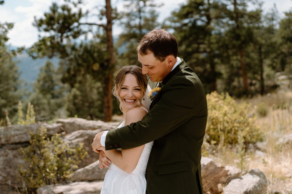 Bride laughing and hugging groom at Mt. Falcon on wedding day