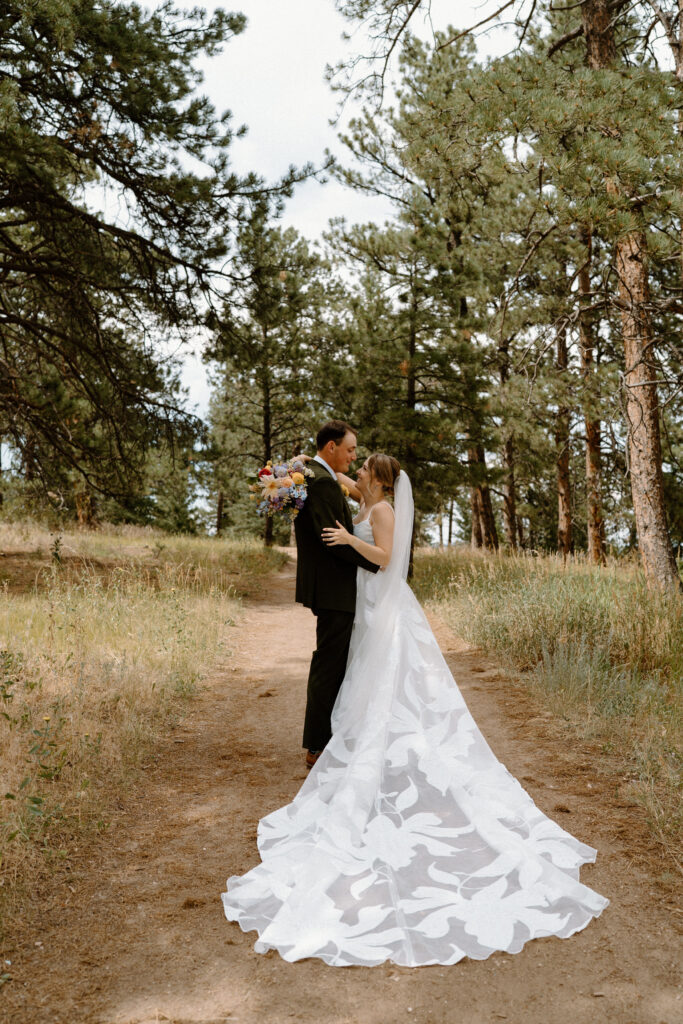 Bride and groom hugging on trail on wedding day at Mt. Falcon