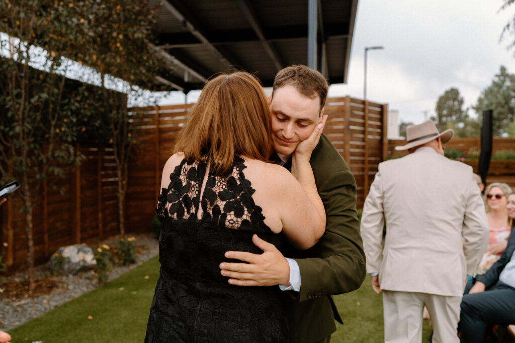 Groom's mom kissing his cheek on wedding day at Mountain Crust