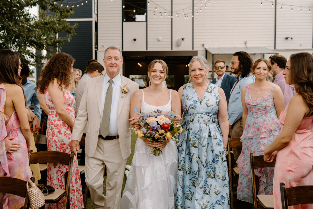 Bride walking down the aisle with parents on wedding day at Mountain Crust
