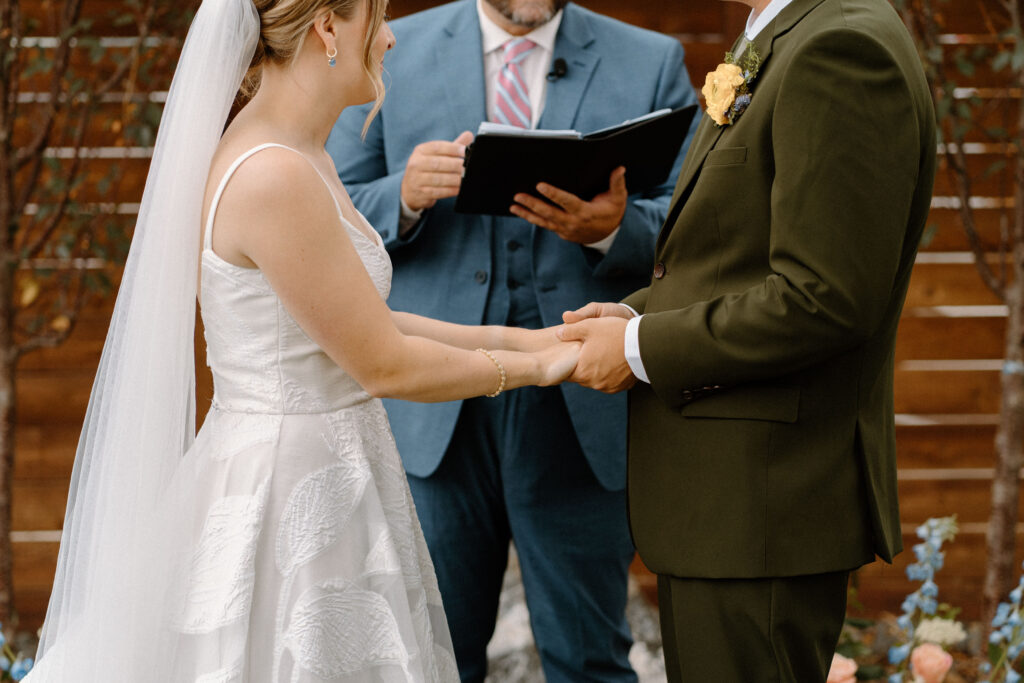 Bride and groom holding hands during wedding ceremony at Mountain Crust