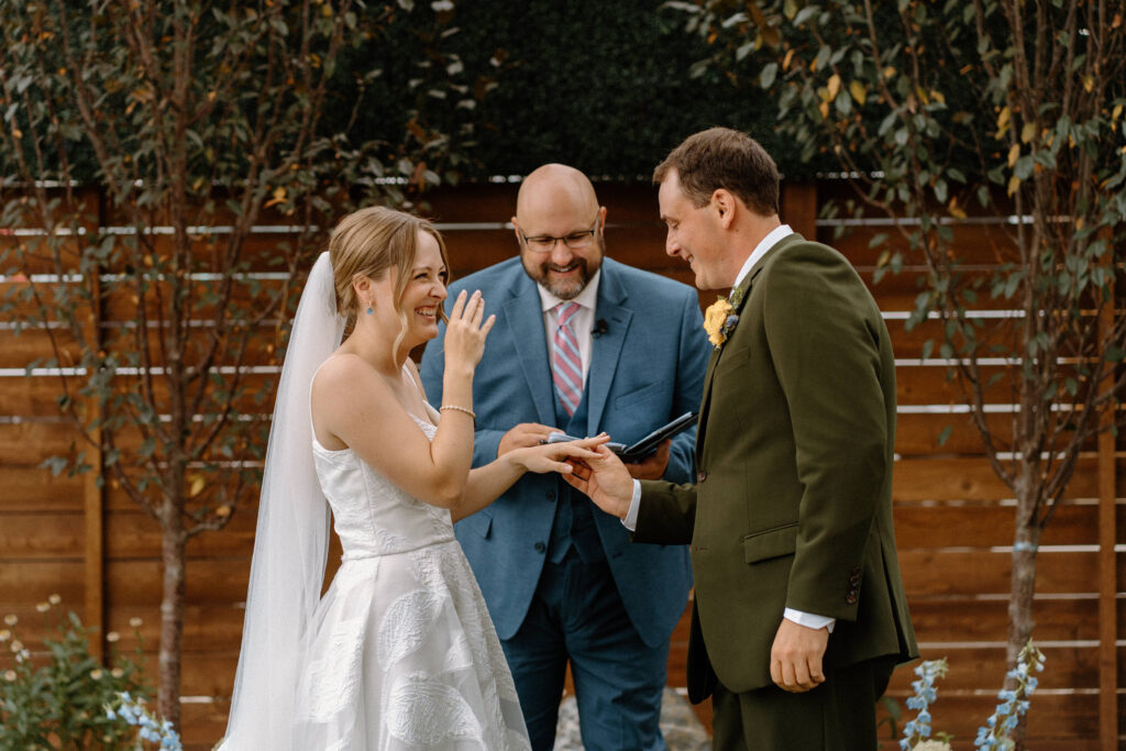 Groom putting bride's ring on during ceremony at Mountain Crust