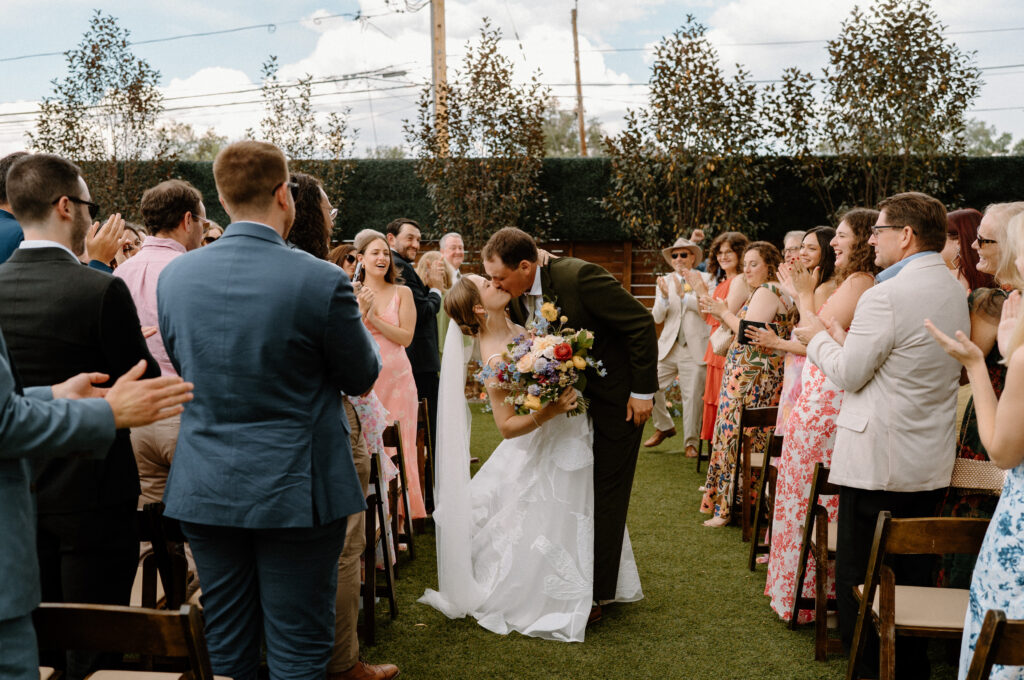 Groom kissing bride at the end of aisle after ceremony at Mountain Crust