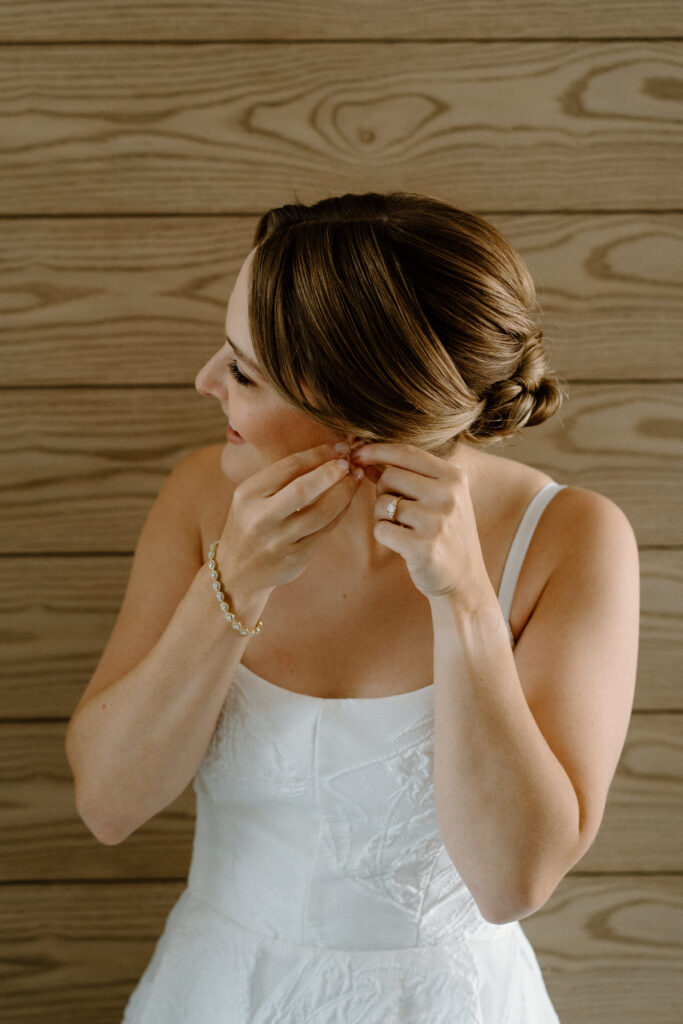 Bride putting earrings in on wedding day at the Maven in Denver