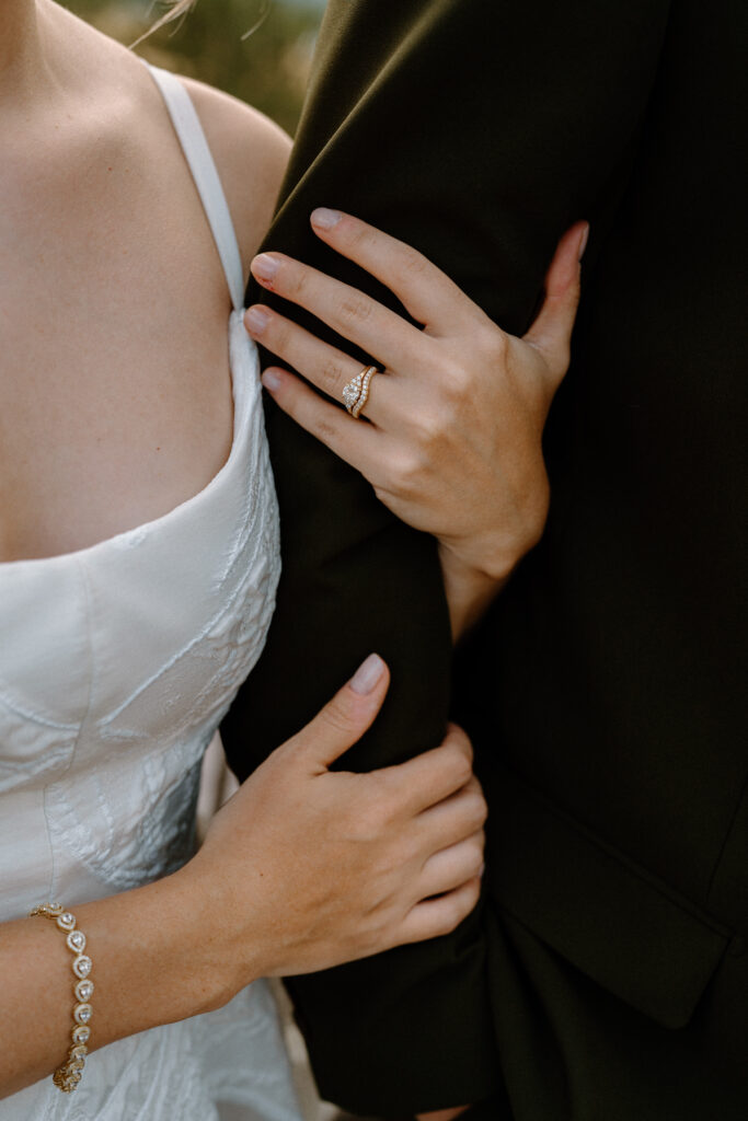 Bride holding groom's arm showing wedding bands at Mountain Crust