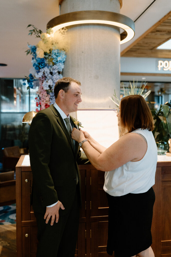 Groom's mom putting on his boutonniere on wedding day at the Marvin Hotel in Denver