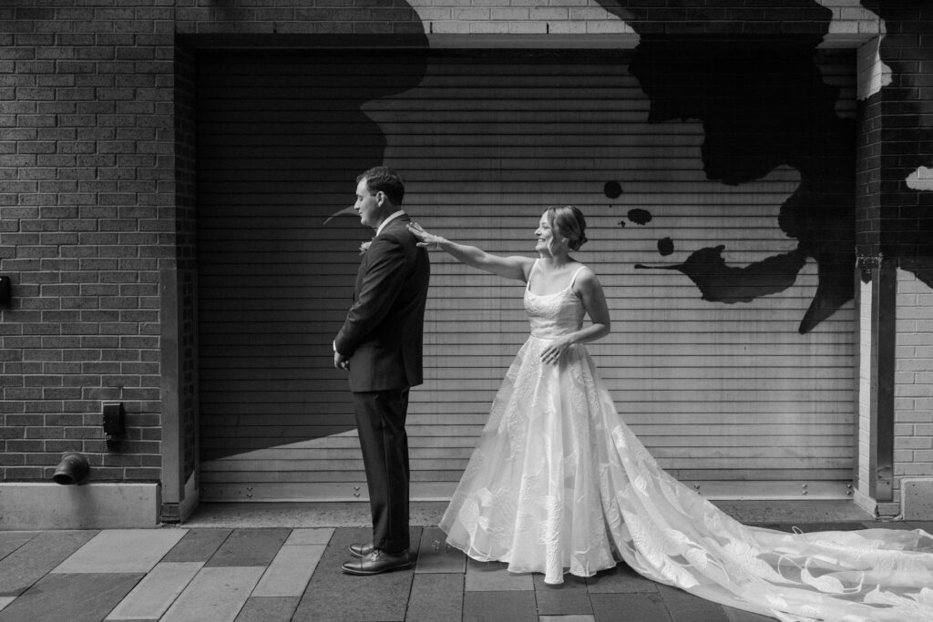 Bride tapping on grooms shoulder during first look on wedding day