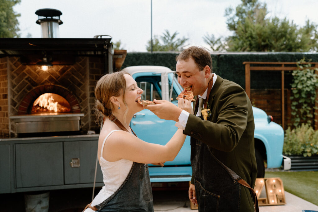 Bride and groom feeding each other pizza on wedding day at Mountain Crust