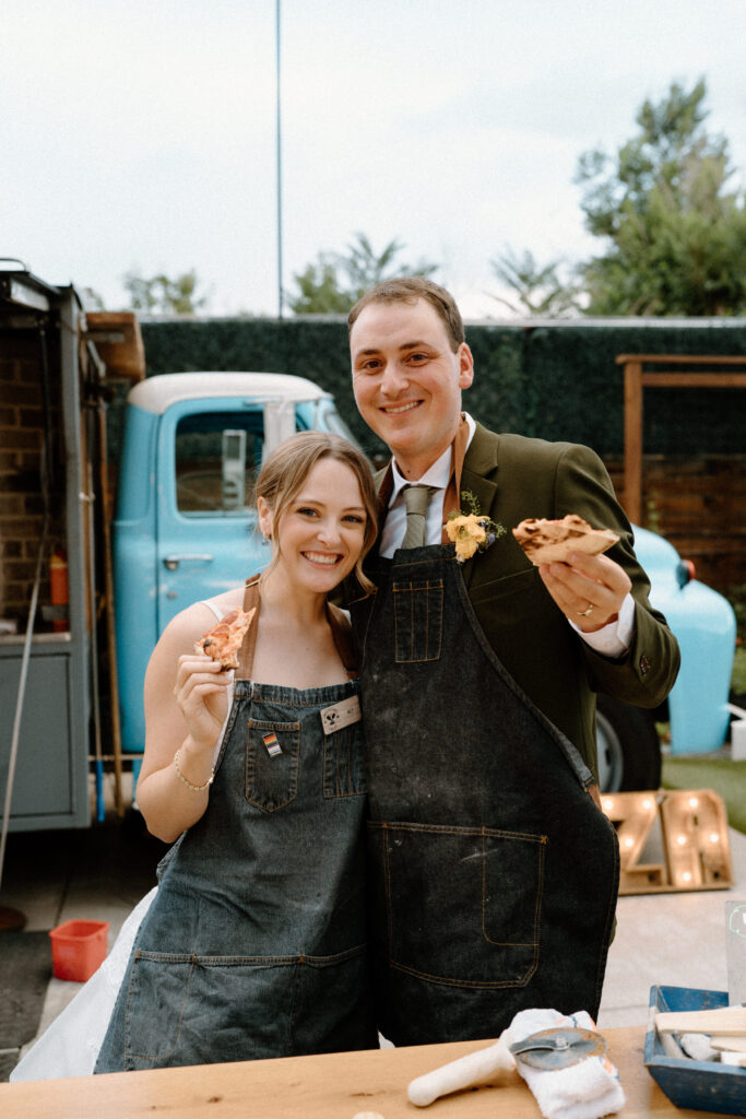 Bride and groom smiling with pizza on wedding day at Mountain Crust