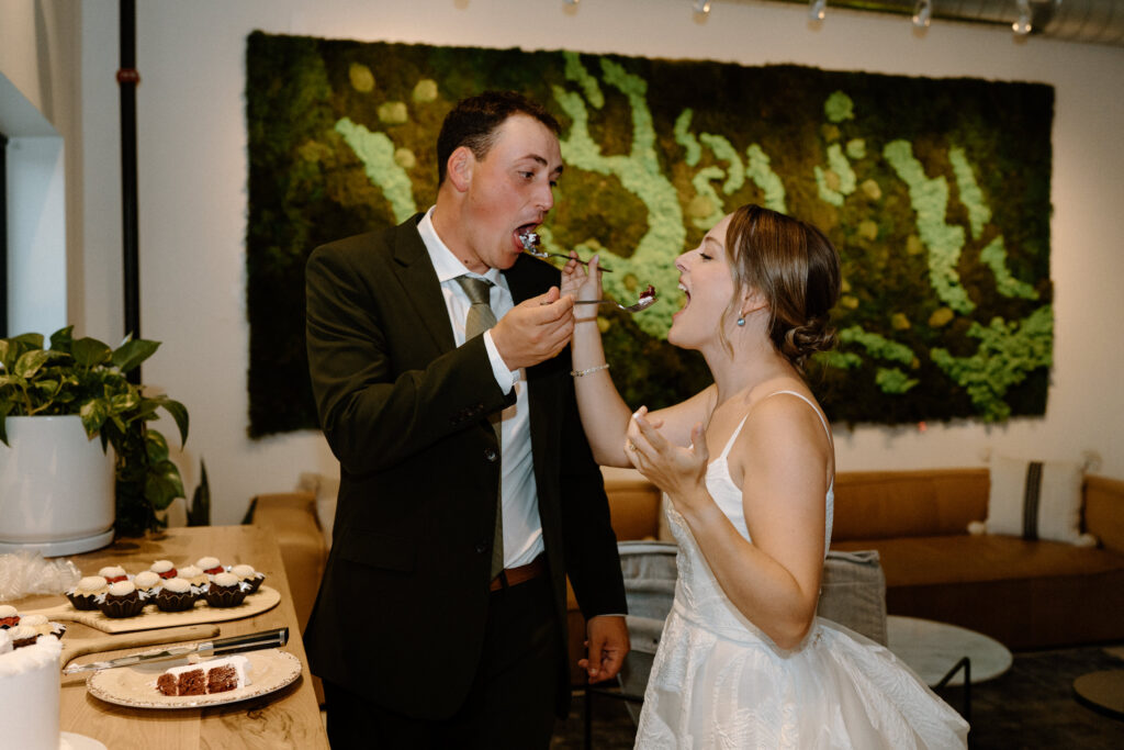 Bride and groom feeding each other cake on wedding day at Mountain Crust
