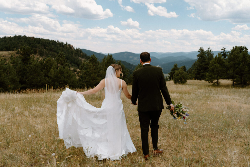 Bride and groom walking in a field on wedding day at Mt. Falcon 