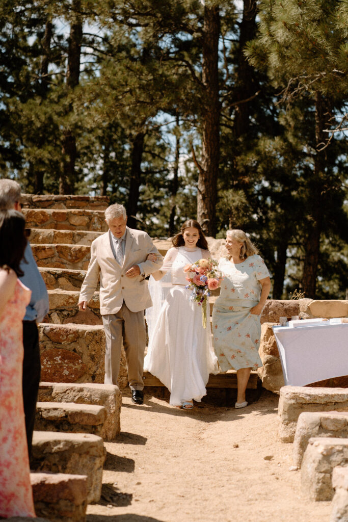 Bride walking down the aisle with parents at Sunrise Amphitheater 