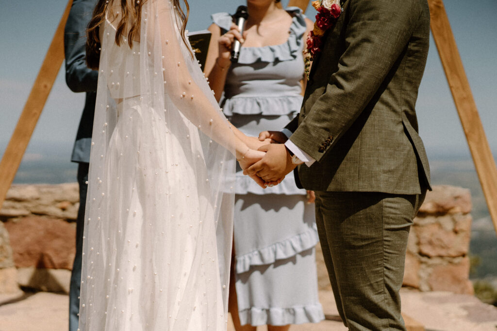 Couple holding hands during ceremony at Sunrise Amphitheater 