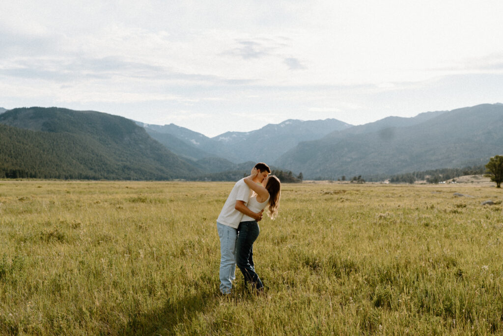 Couple kissing in a field at Rocky Mountain National Park during an engagement session
