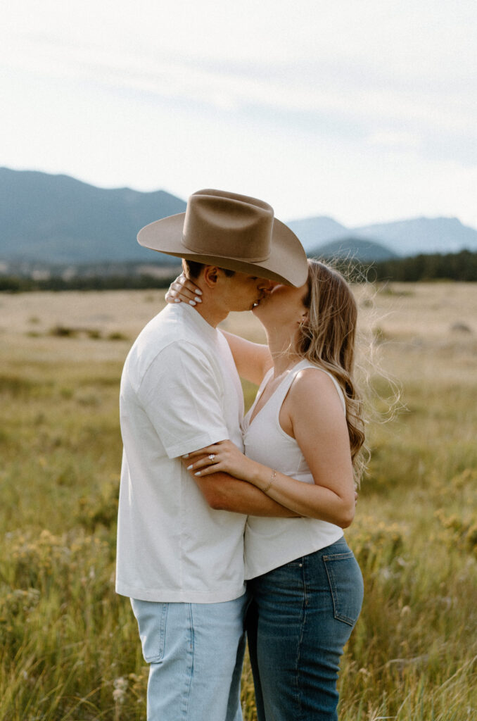 Couple kissing in a field at Rocky Mountain National Park during engagement session