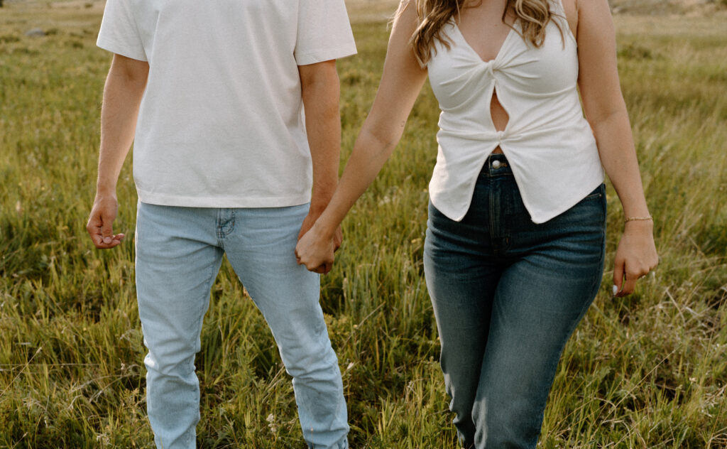 Close-up of couples outfits while holding hands at Rocky Mountain National Park during an engagement session