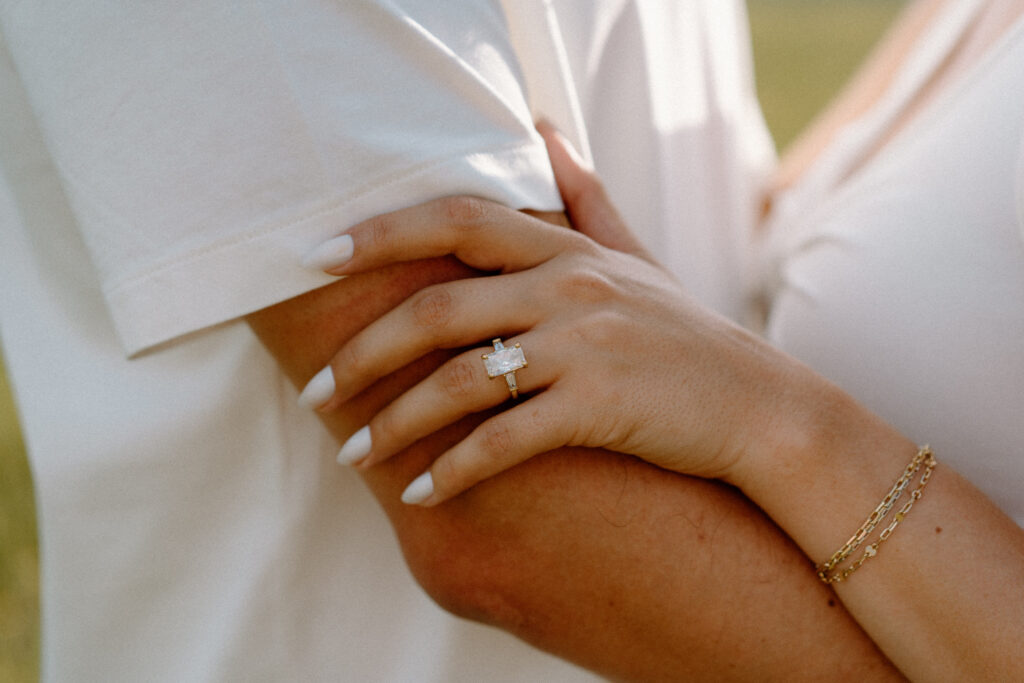 Fiancée holding fiancés arm showing engagement ring during session at Rocky Mountain National Park