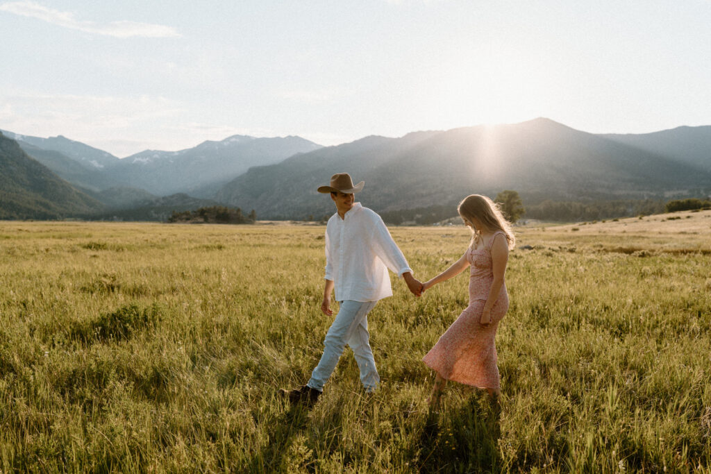 Couple holding hands at Rocky Mountain National Park while hiking during engagement session
