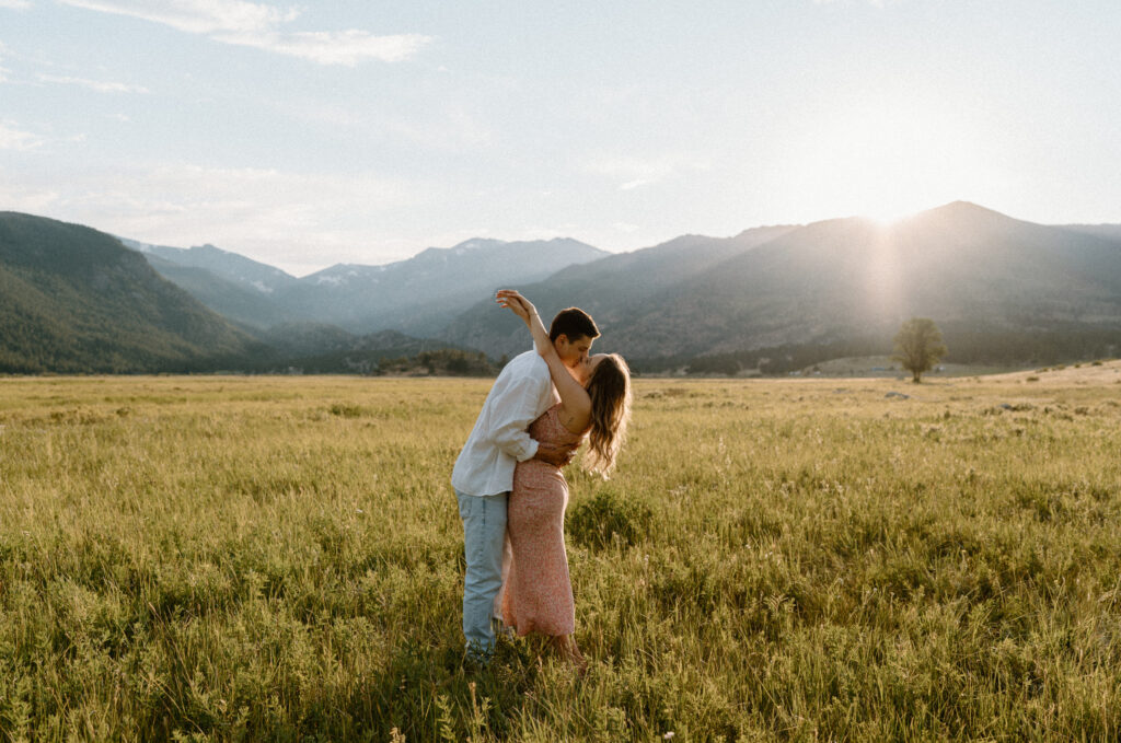 Couple kissing in a field at Rocky Mountain National Park during engagement session